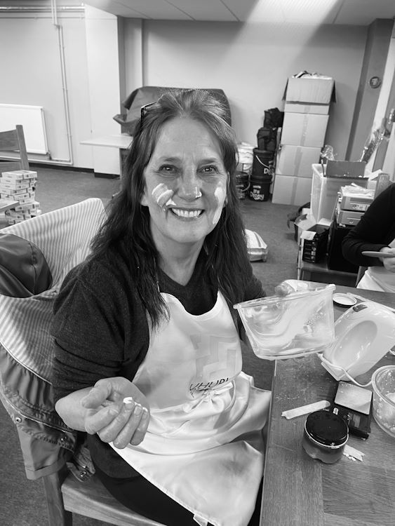 Student smiling at the camera while formulating their own cosmetics.